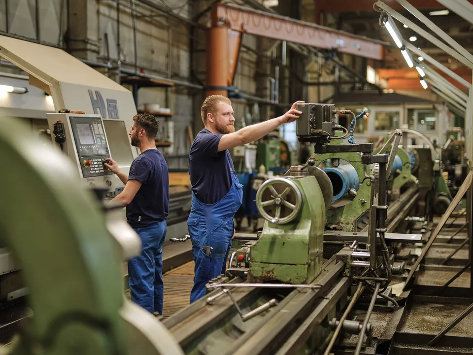 Zwei Mitarbeiter richten gemeinsam eine konventionelle Drehmaschine ein