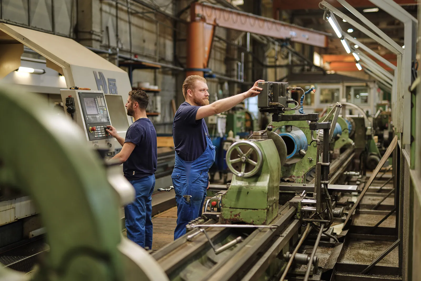 Zwei Mitarbeiter richten gemeinsam eine konventionelle Drehmaschine ein