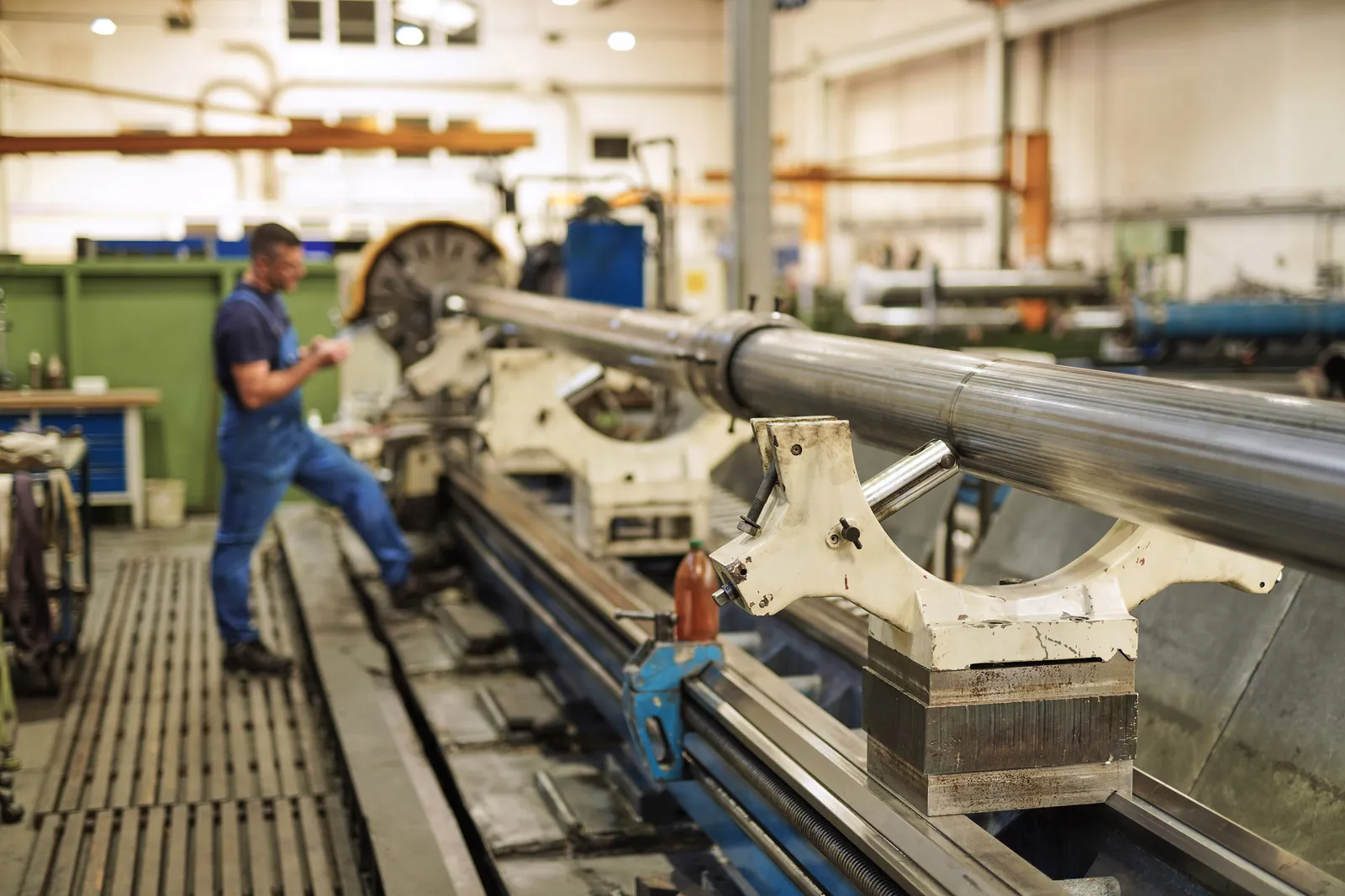 Mitarbeiter bearbeitet eine mehrere Meter lange Kolbenstange auf der Drehmaschine