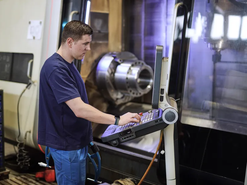 Mitarbeiter programmiert am Bedienpult einer CNC-Drehmaschine