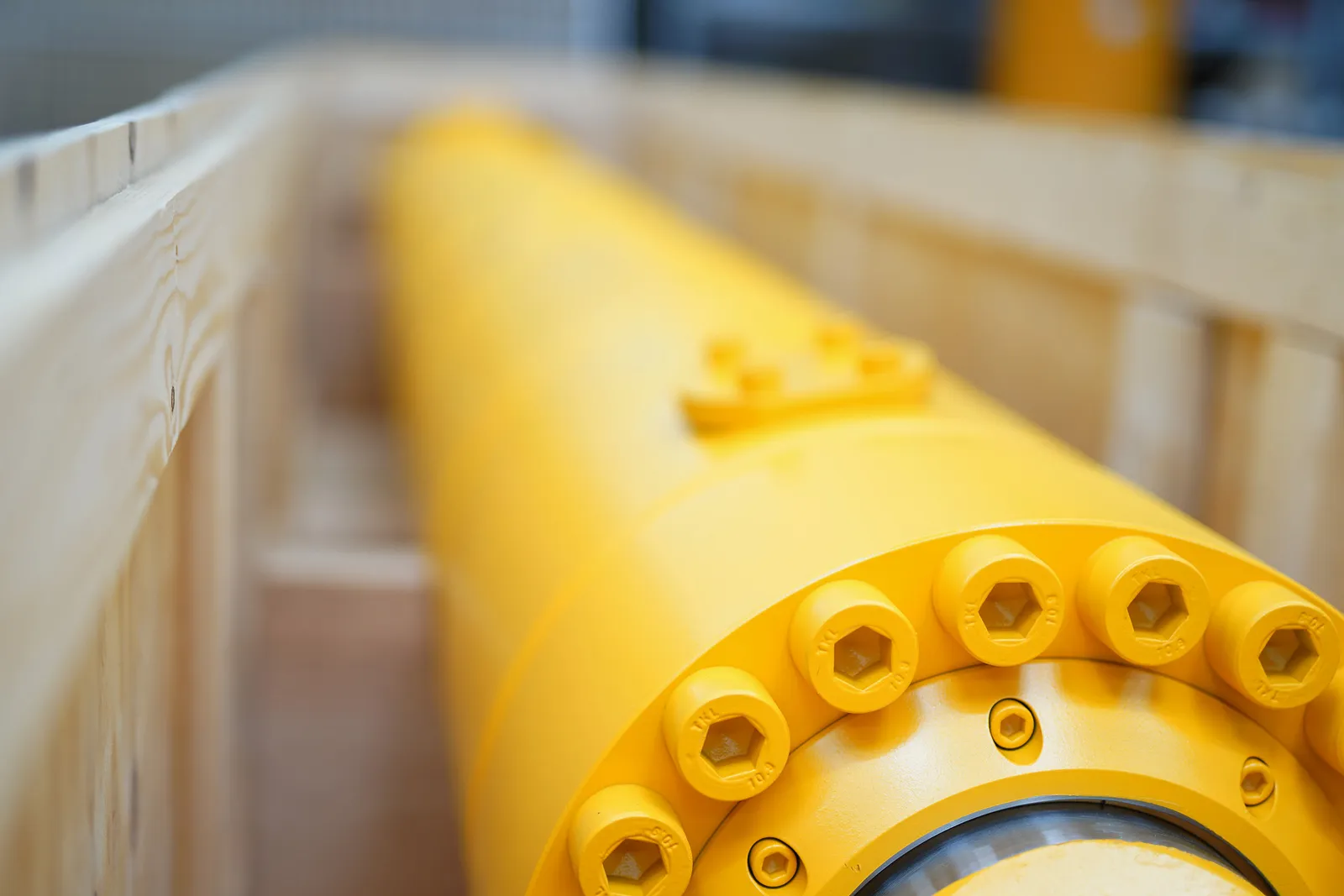 Nahaufnahme des Flansches eines gelben Hydraulikzylinders mit Schraubenkranz
